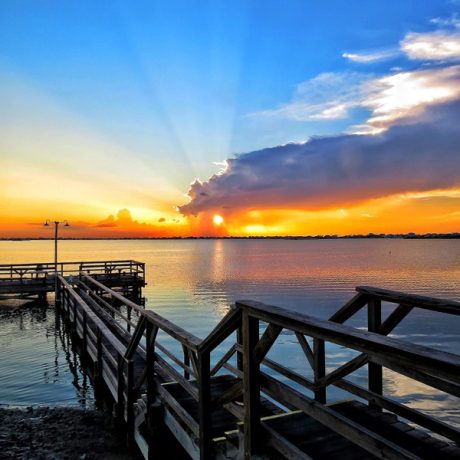 A serene dock at sunset, illuminated by the sun, located at Copano Bay RV Resort in Rockport, TX.