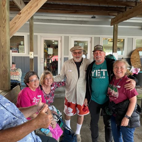 A group of people smiling and posing for a photo in front of the Copano Bay RV Resort building in Rockport, TX.