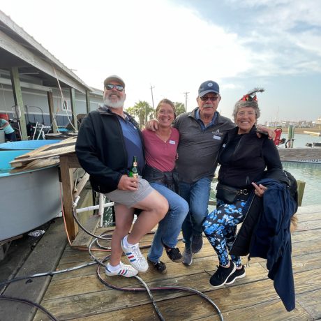 Three individuals pose for a photo on a dock at Copano Bay RV Resort in Rockport, Texas, with water in the background.