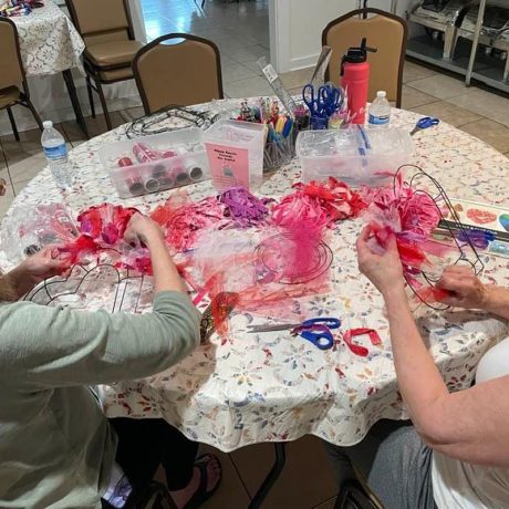 Two women engaged in crafting at a table in Copano Bay RV Resort, Rockport, TX, showcasing creativity and collaboration.