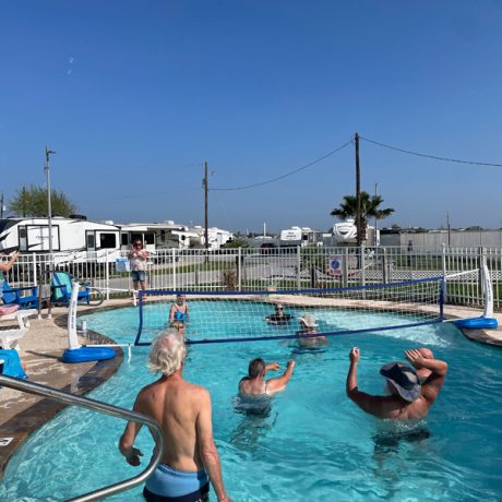 People engage in a fun volleyball match in a pool at Copano Bay RV Resort, located in Rockport, TX.