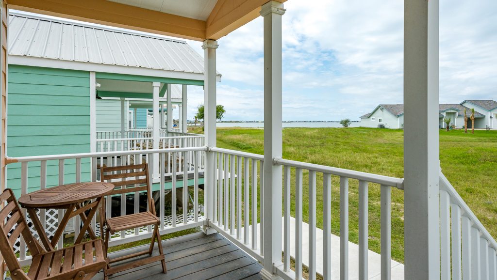 A cozy porch at Cabins at Copano Bay RV Resort, featuring two chairs and a table, perfect for relaxation in Rockport, TX.