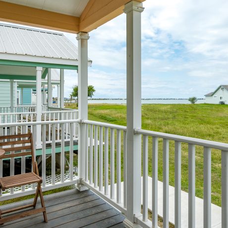 A cozy porch at Cabins at Copano Bay RV Resort, featuring two chairs and a table, perfect for relaxation in Rockport, TX.