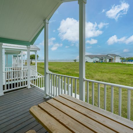 A serene porch at Copano Bay RV Resort features a table and chairs with a view of the beach in Rockport, TX.