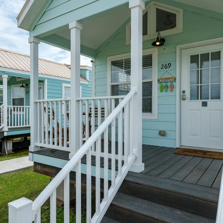 Cozy blue house with a porch and stairs situated at Copano Bay RV Resort in Rockport, Texas.